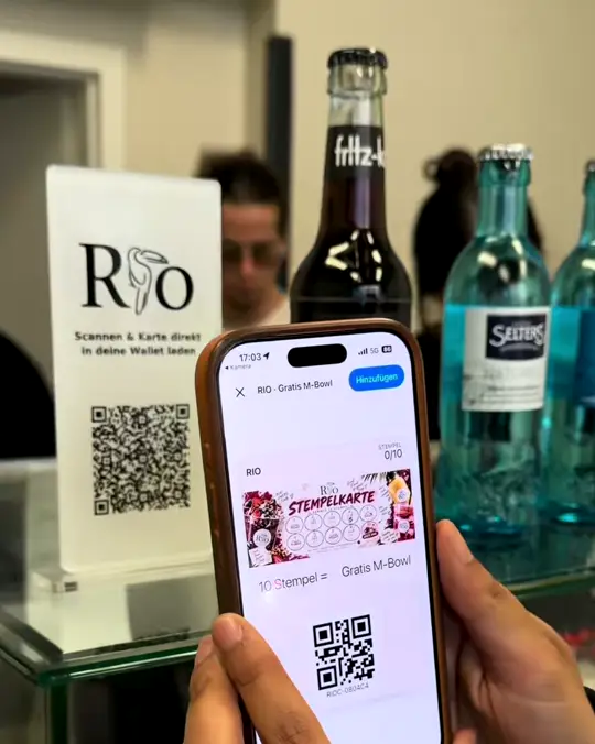 Handy mit der digitalen RIO-Stempelkarte vor dem QR-Aufsteller an der Kasse