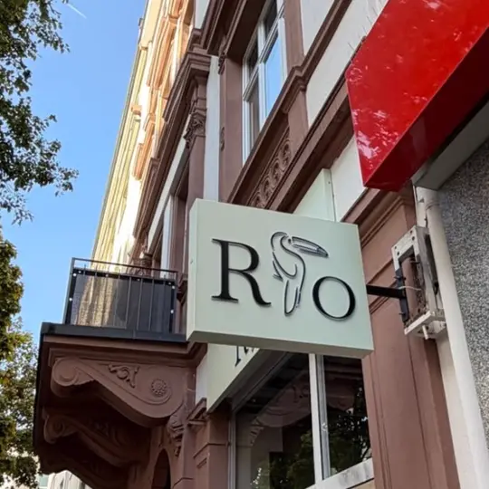 Das neue RIO-Schild mit Tukan an der Sandsteinfassade der Berger Straße
